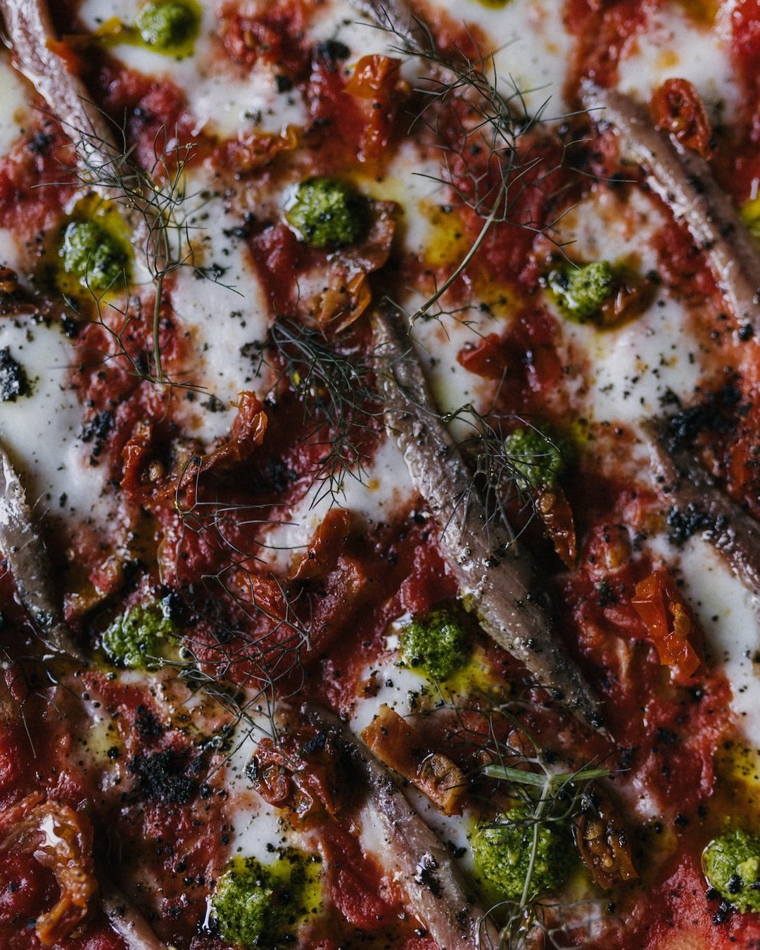 Dettaglio di pizza con alici e pesto
