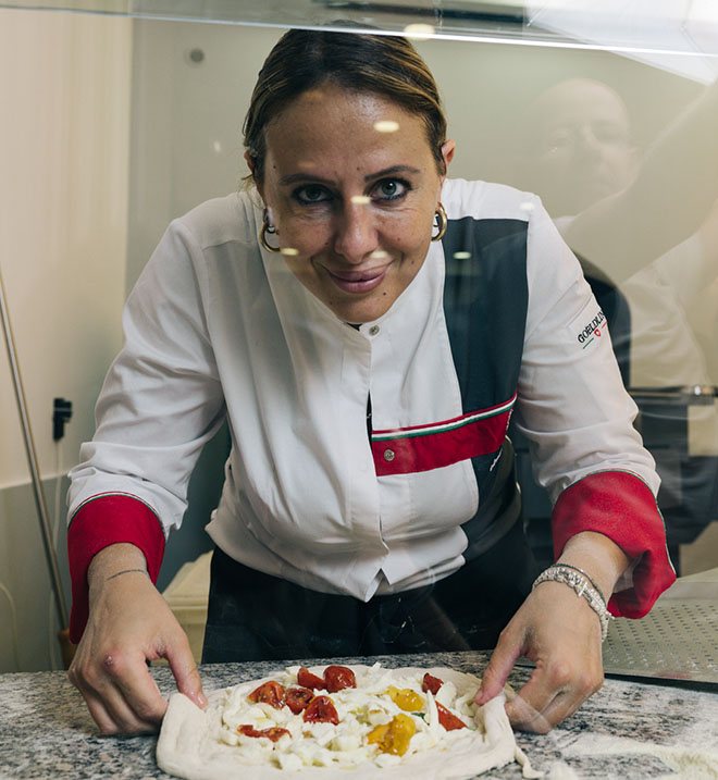 Roberta Esposito sorride mentre stende una pizza